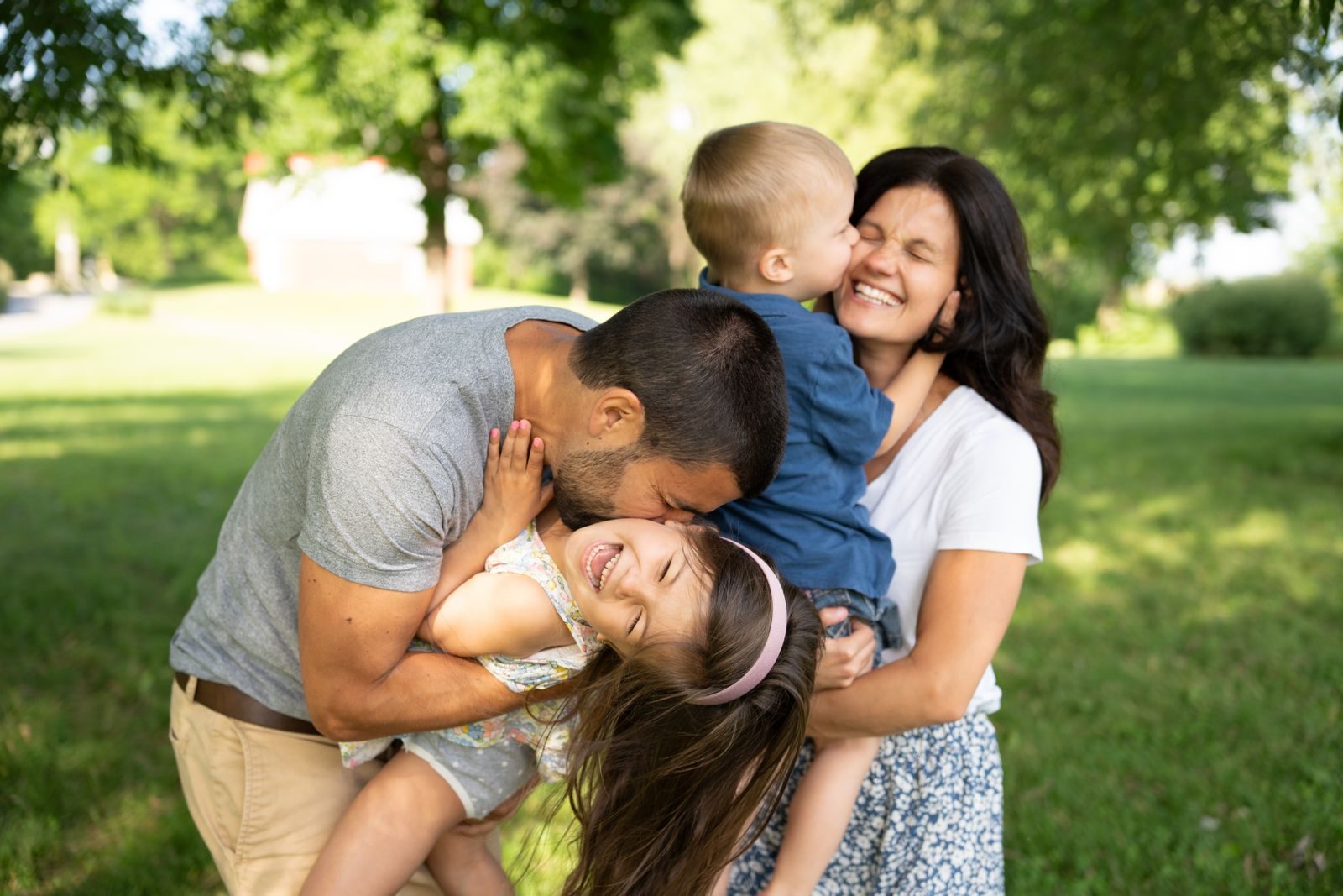 A family laughing together outdoors, embracing